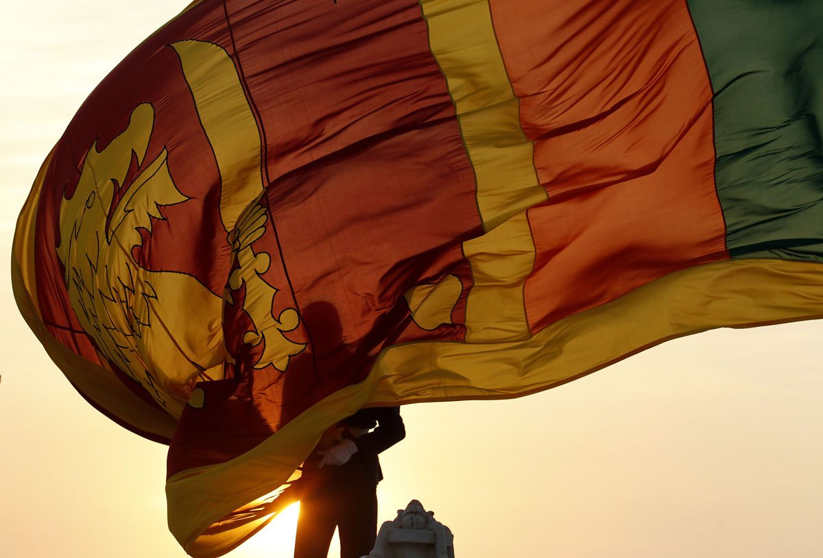 Air force officer holds Sri Lanka’s national flag as the sun sets at Galle Face Green in Colombo